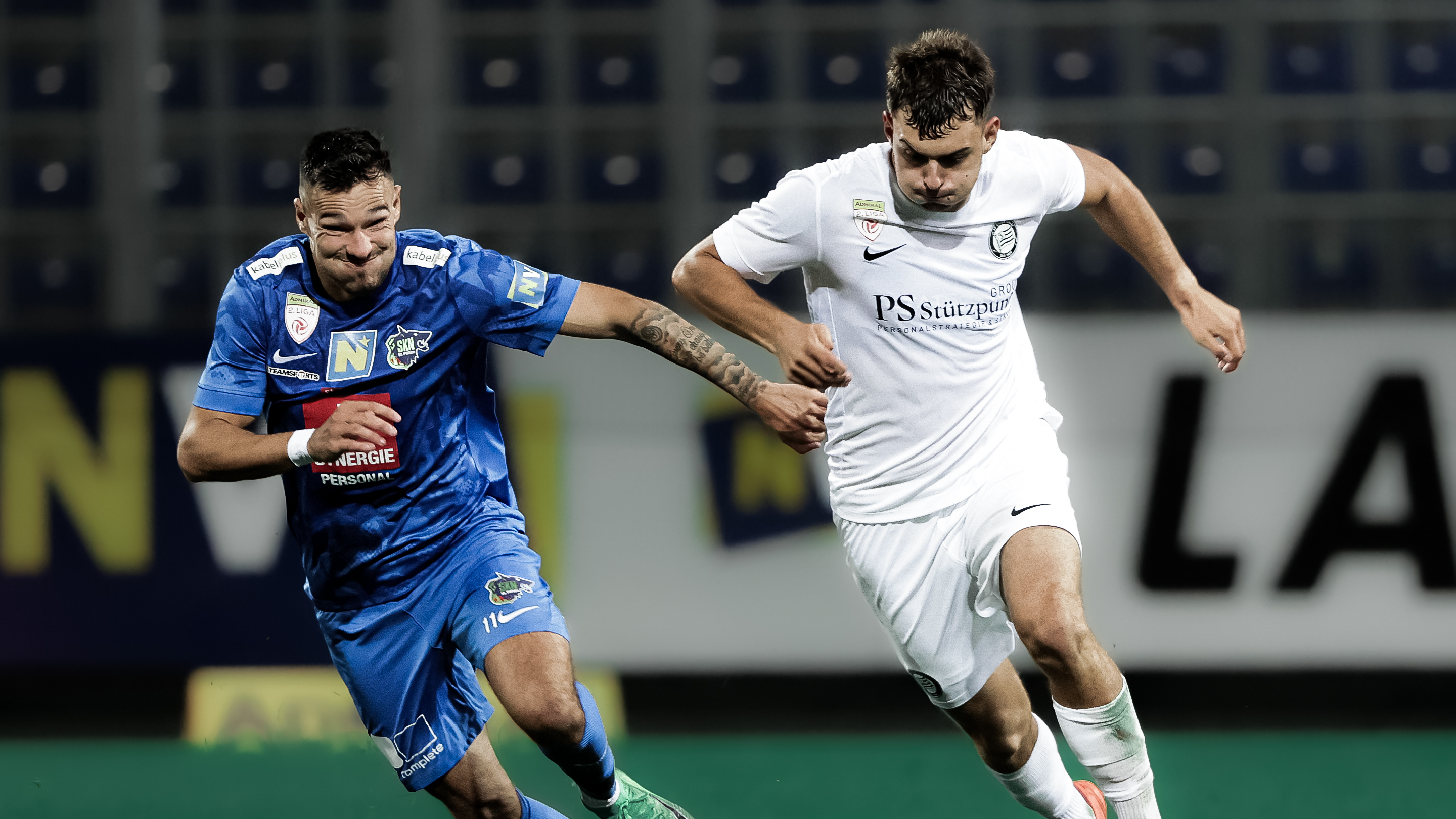 Ein Spieler in weiß und ein Spieler in blau kämpfen um den Ball
