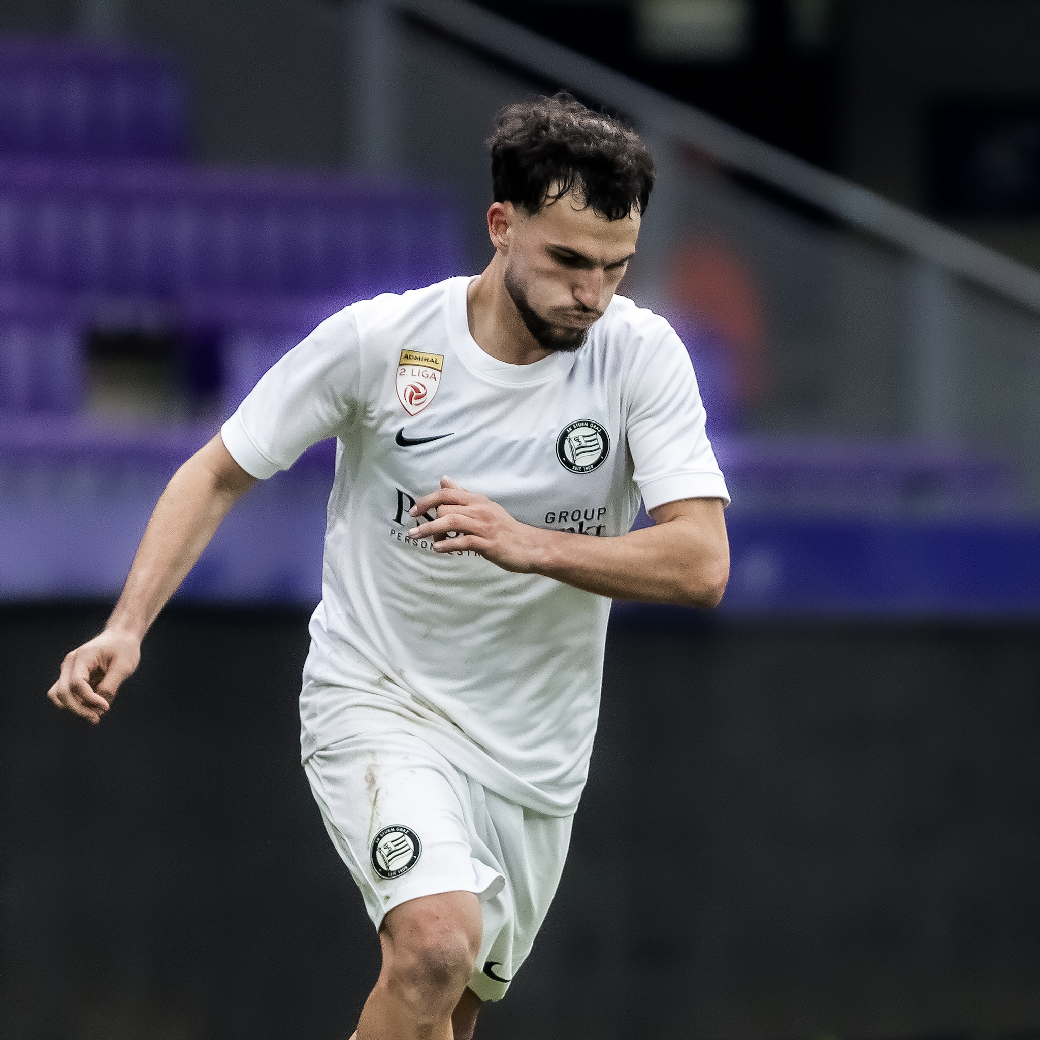 Ein Spieler in einem weißen Trikot führt einen Ball.