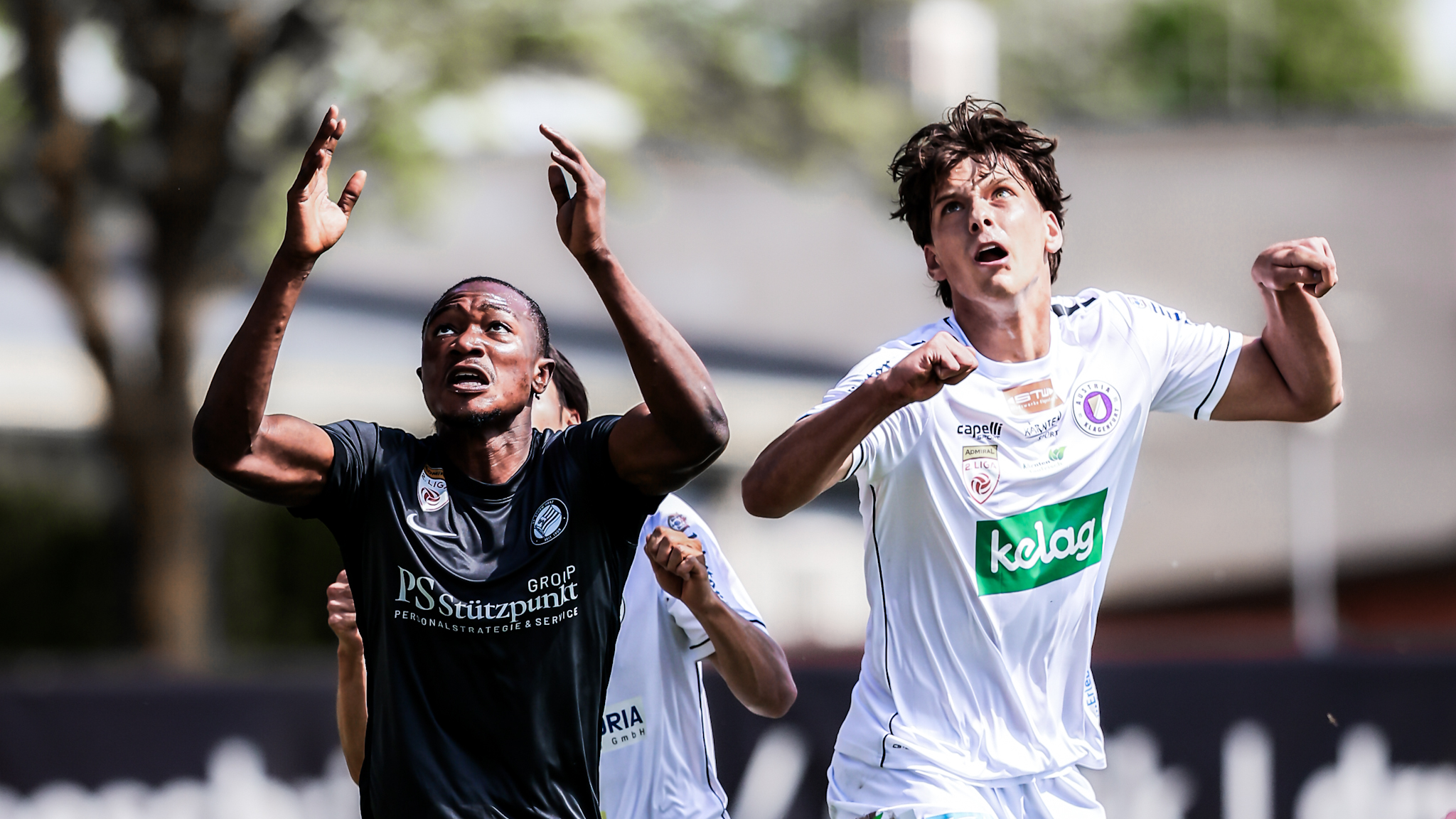 Ein Spieler in schwarz und ein Spieler in weiß kämpfen um einen Ball in der Luft