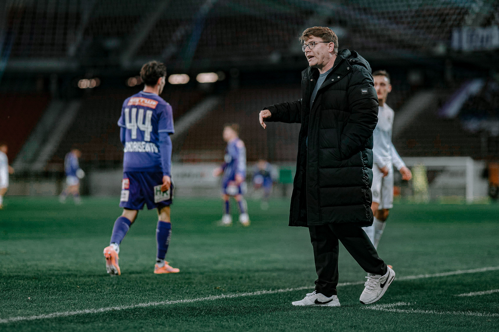 Ein Fußballtrainer steht am Spielfeldrand.