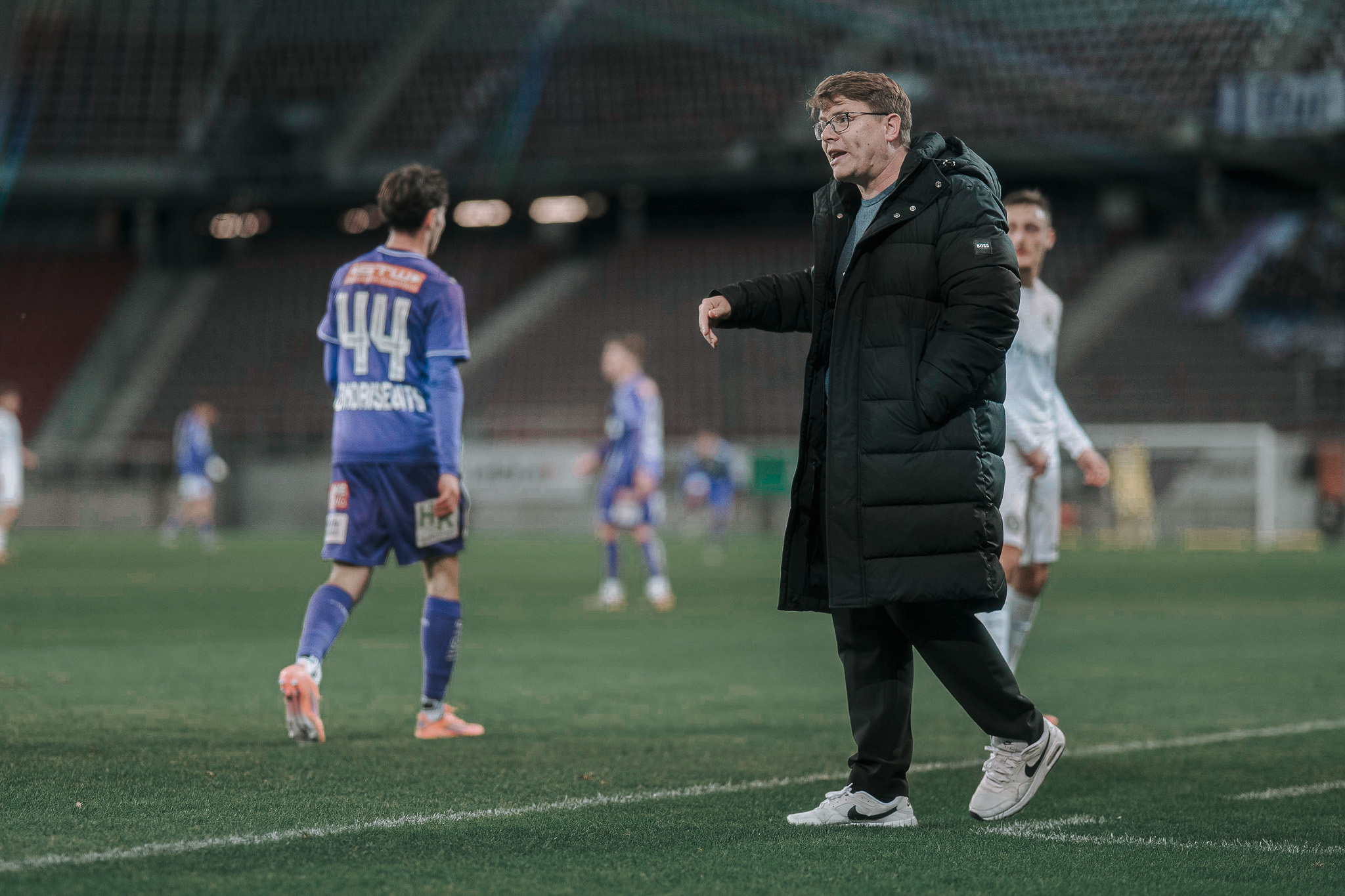 Ein Fußballtrainer steht am Spielfeldrand.