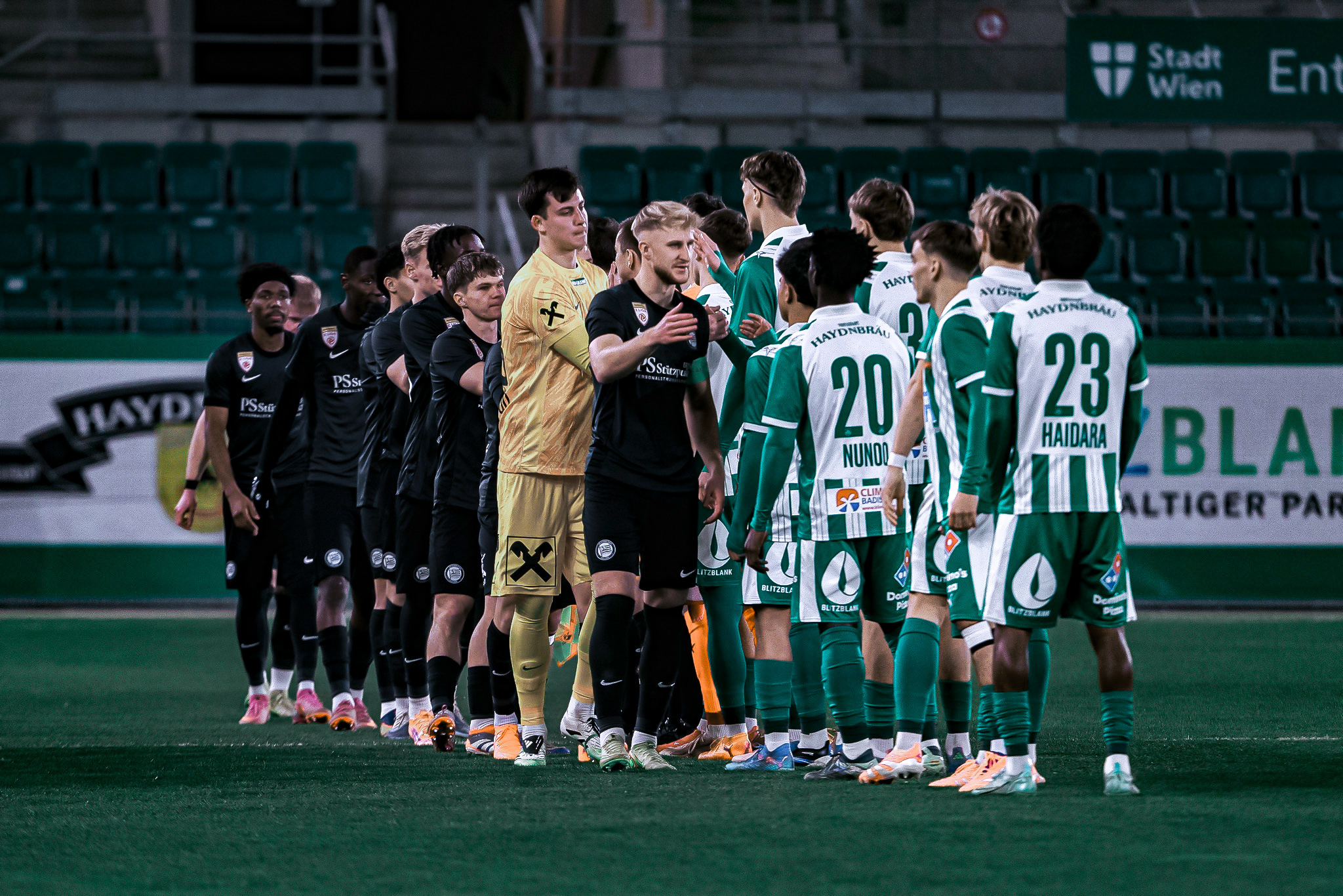 Zwei Fußballteams begrüßen sich.