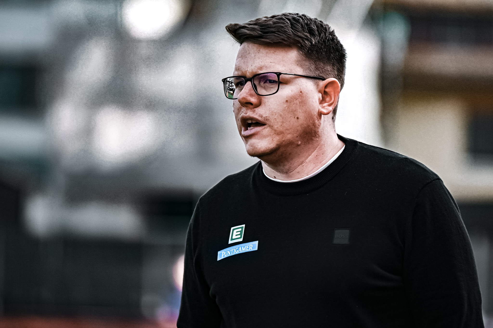 Ein Mann mit Werbeaufkleber und Brille spricht.