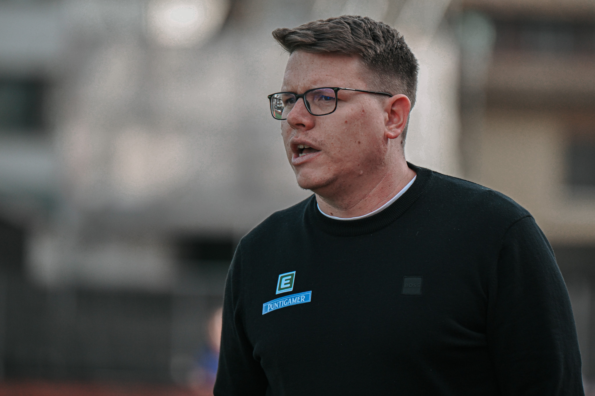Ein Mann mit Werbeaufkleber und Brille spricht.